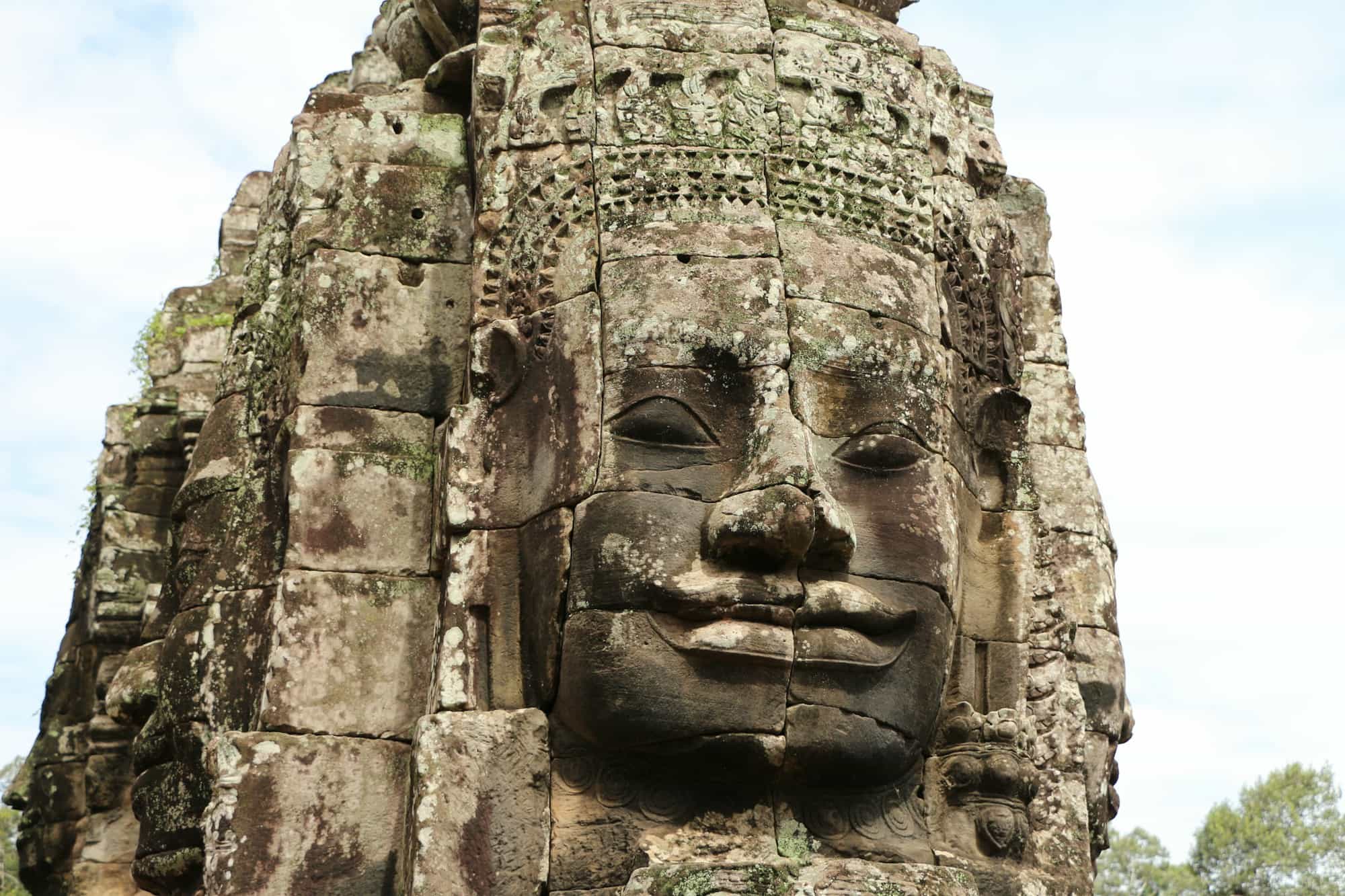Giant smiling stone face on a tower of Bayon Temple