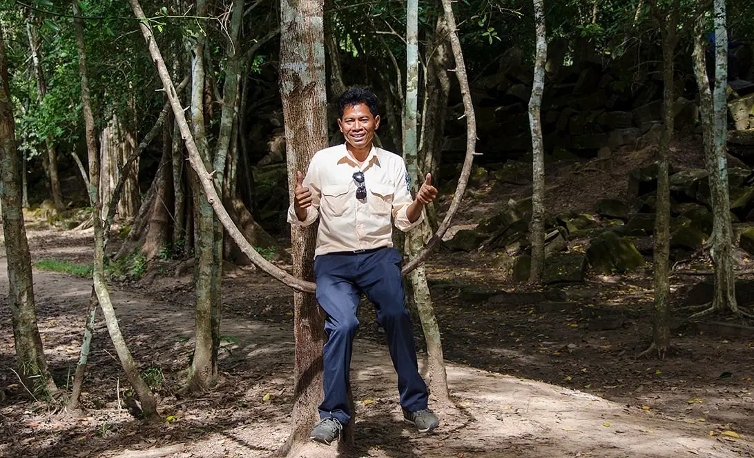 San Park standing among hanging vines in the forest at Ta Prohm